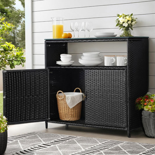 Black wicker sideboard with diningware on a patio