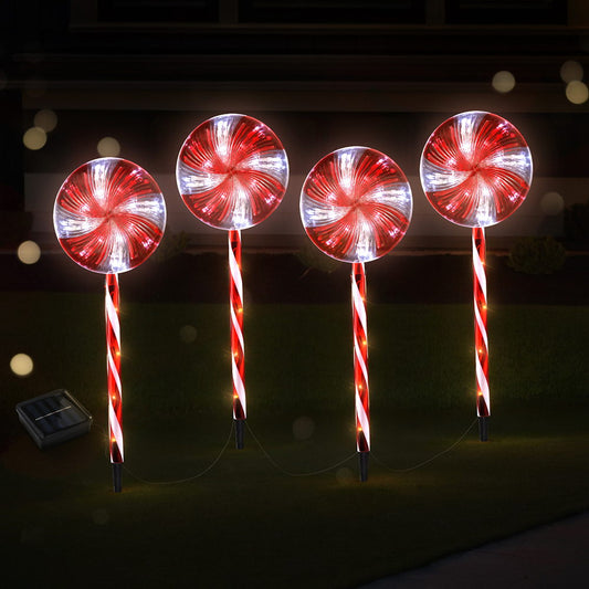 Four red and white striped lollipop-shaped lights on stakes against a dark background.