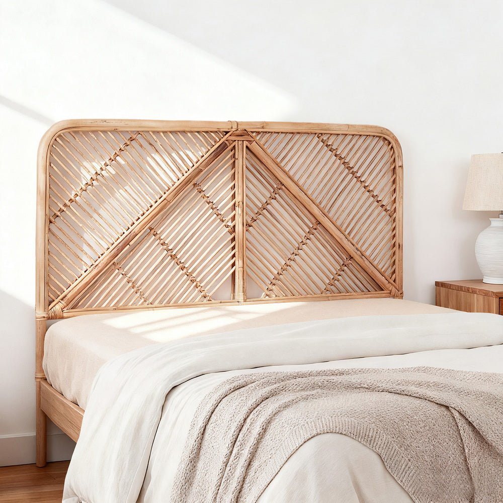 Woven rattan headboard on a bed with a white wall and lamp in the background