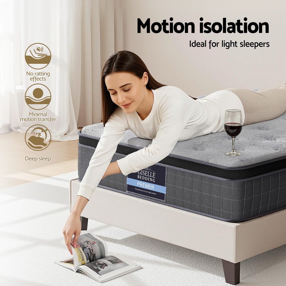 Woman lying on a mattress with a glass of wine and a magazine, emphasizing motion isolation.