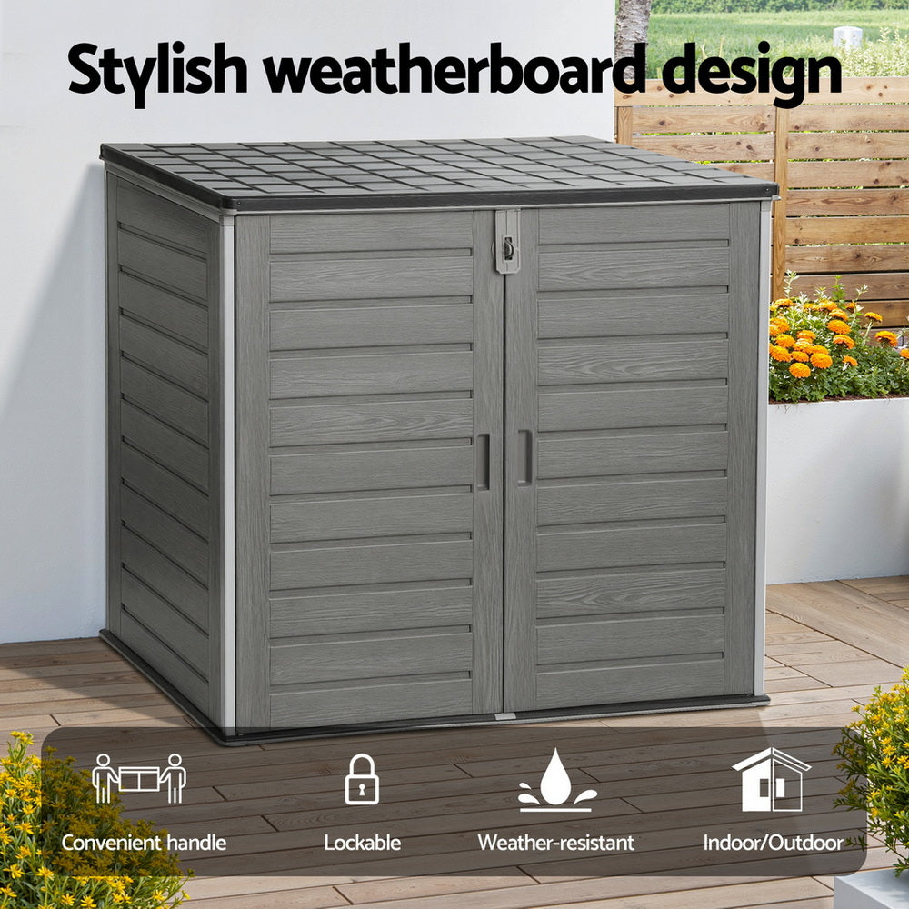 Gray outdoor storage shed with weatherboard design, lockable feature, and indoor/outdoor use, set against a garden background.