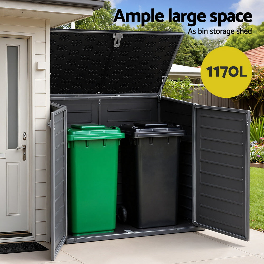 Large outdoor storage shed with open doors showing green and black trash bins, labeled '1170L'.