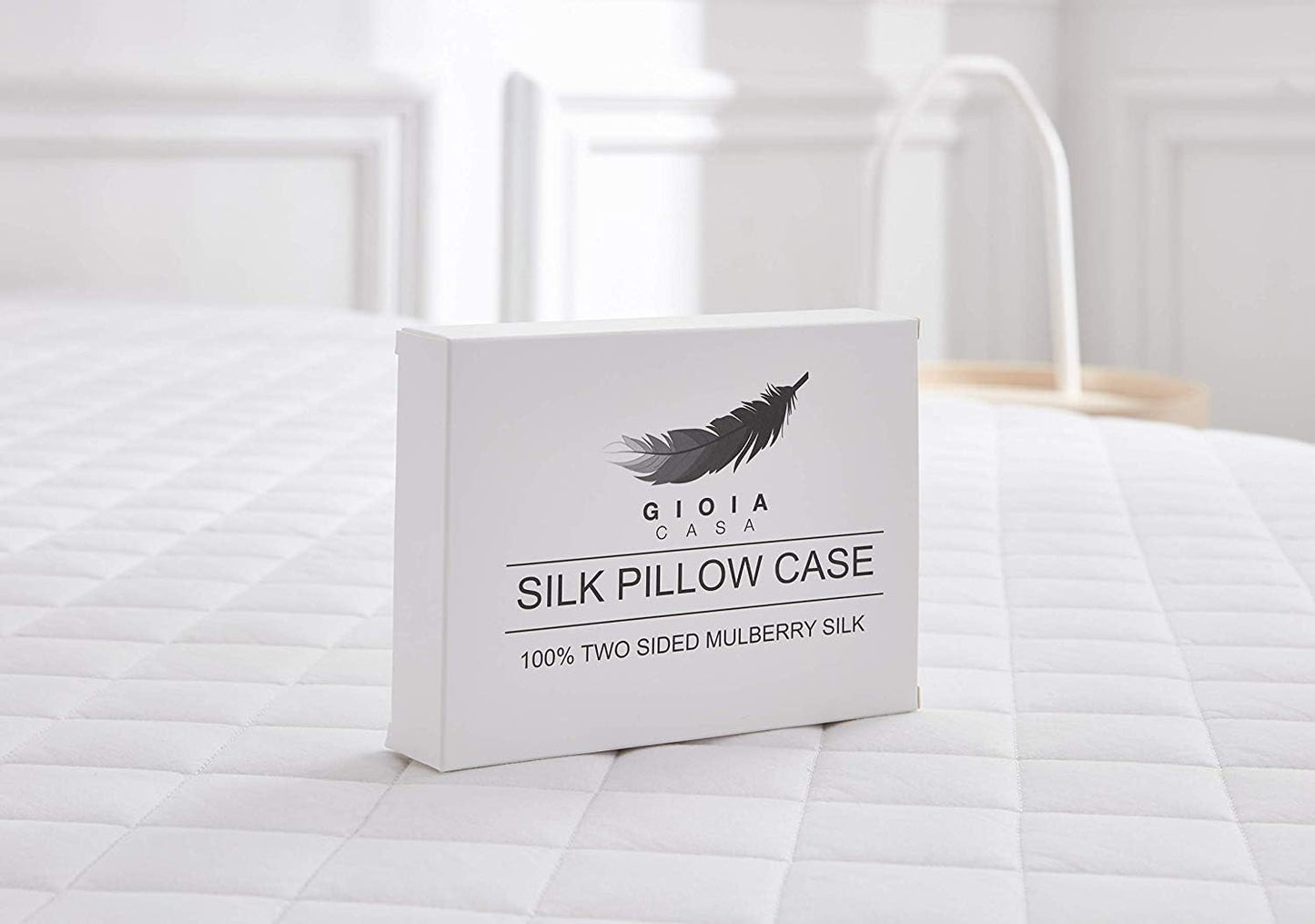Silk pillow case packaging on a bed with a feather design logo.
