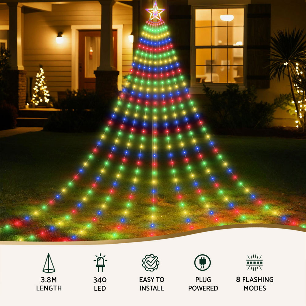 Decorative outdoor Christmas tree made of colorful lights in front of a house.